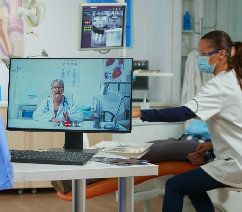 assistent-having-video-call-with-expert-stomatologic-dotor-using-computer-while-doctor-is-working-with-patient-background-nurse-listening-dentist-webcam-sitting-chair-stomatological-offic.jpg
