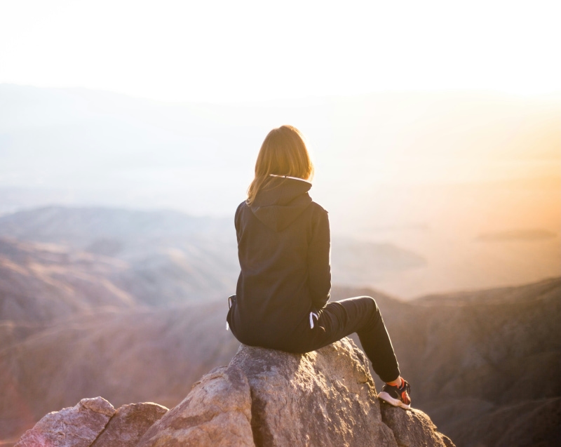 Woman sitting on a rock in the mountains.